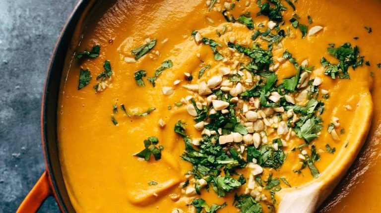 Spicy Carrot Soup in pot with wooden spoon.