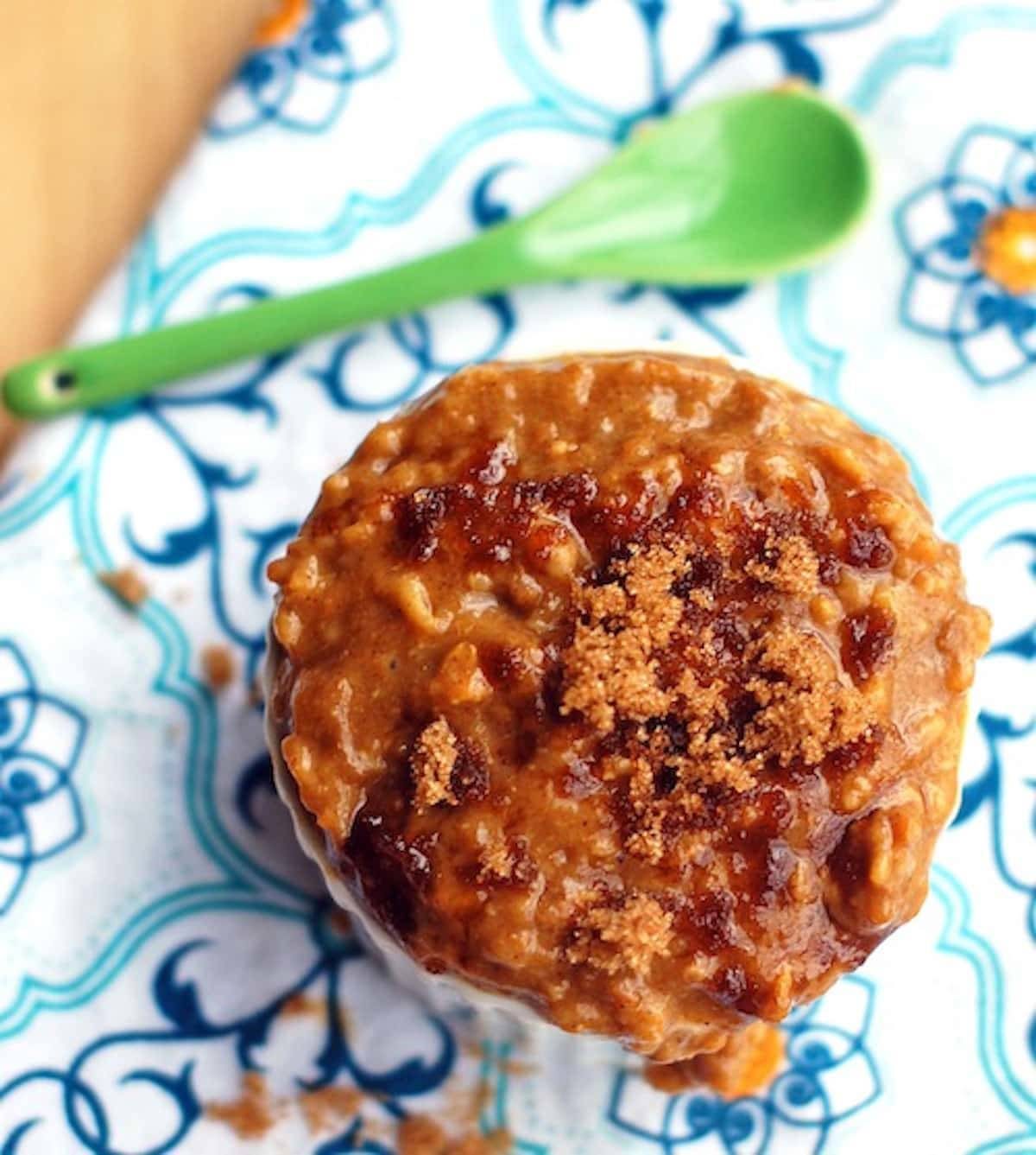 Pumpkin oatmeal with pumpkin, bran, and egg whites on a colorful napkin with a green spoon.