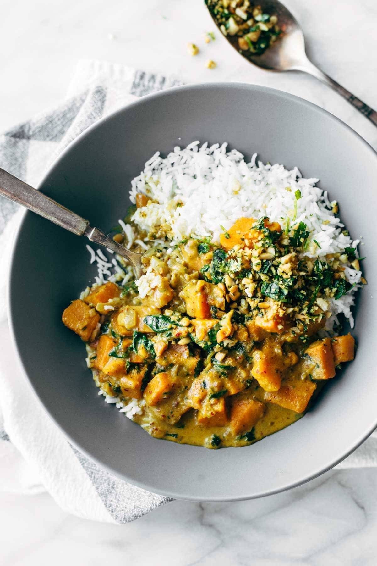Bowl of root vegetables in sauce with rice.