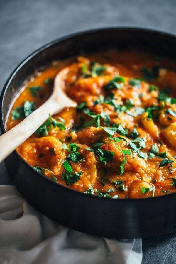 Spanish Chicken and Potatoes in a skillet with a wooden spoon.