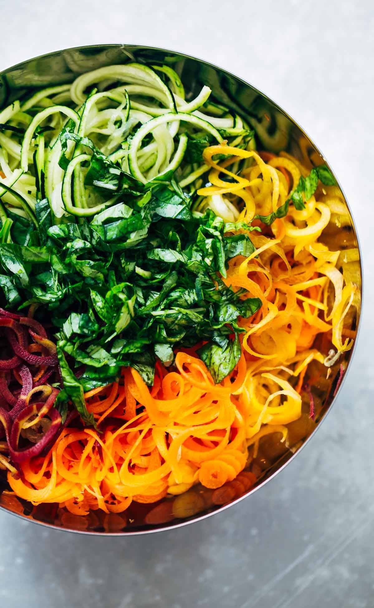 Zucchini, carrots, and basil in a mixing bowl.